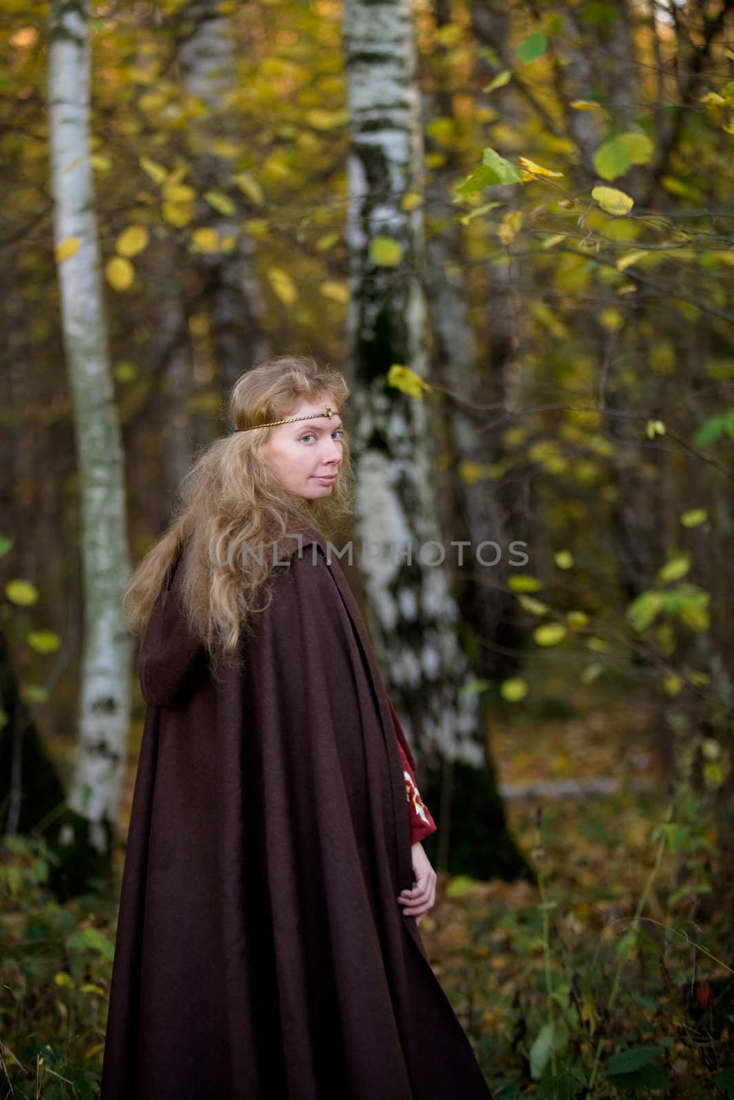 The blonde girl in medieval dress in the autumn forest
