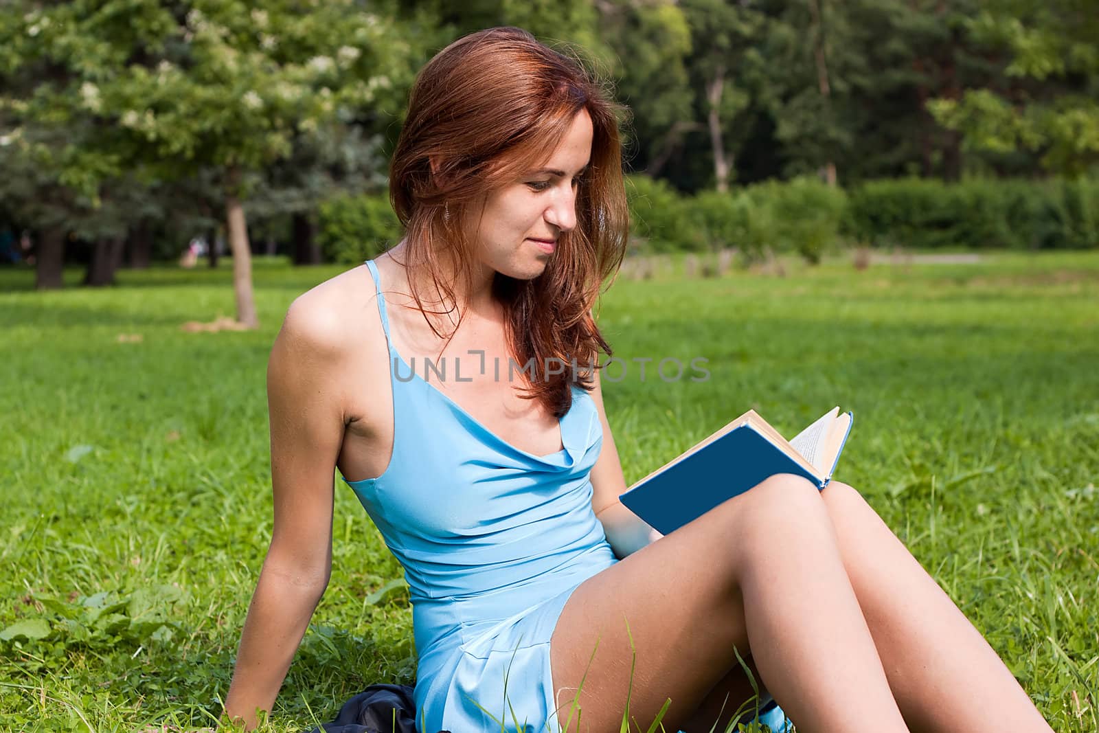 We see young lady reading the book in grass