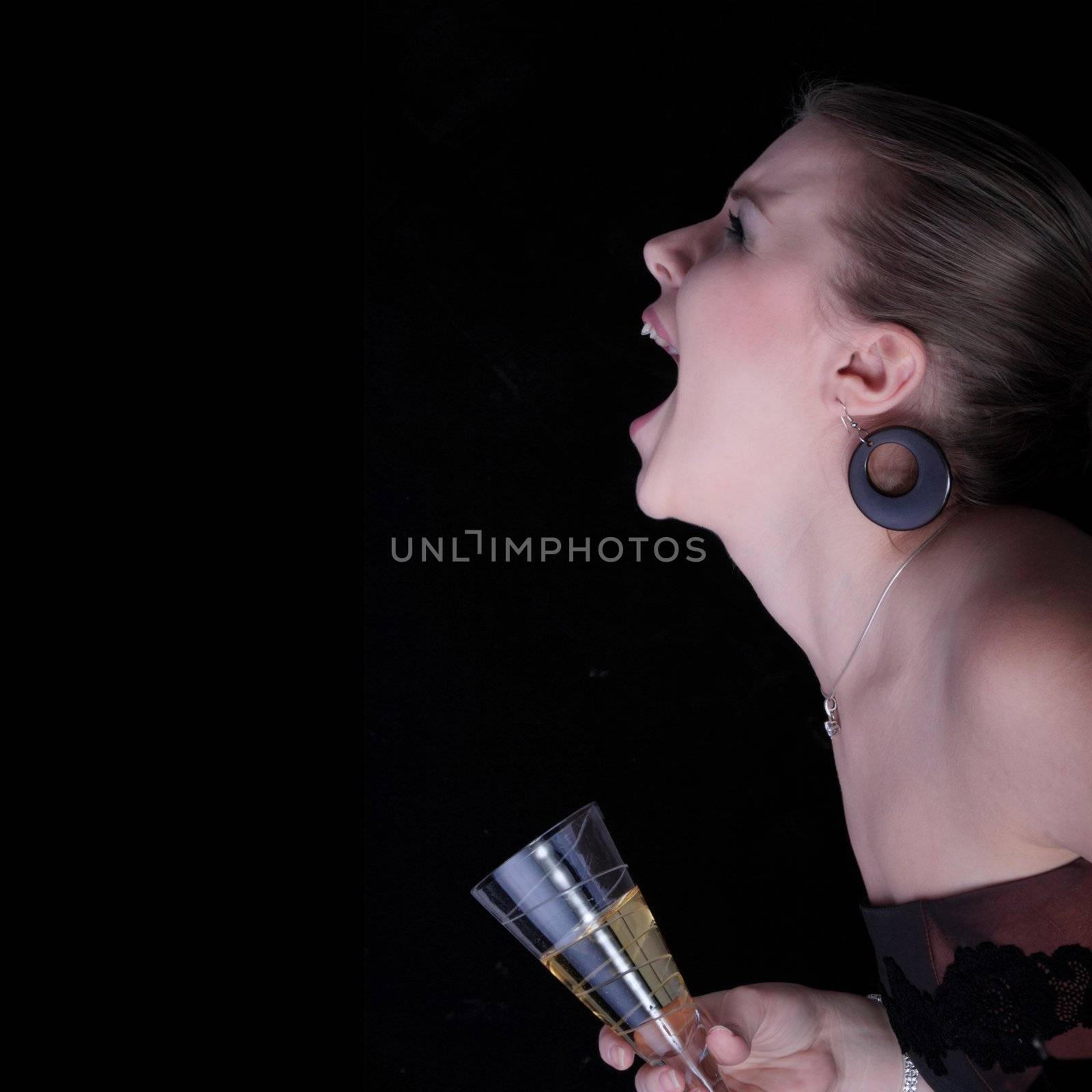 Beautiful blonde with a champagne glass screaming - on black background.