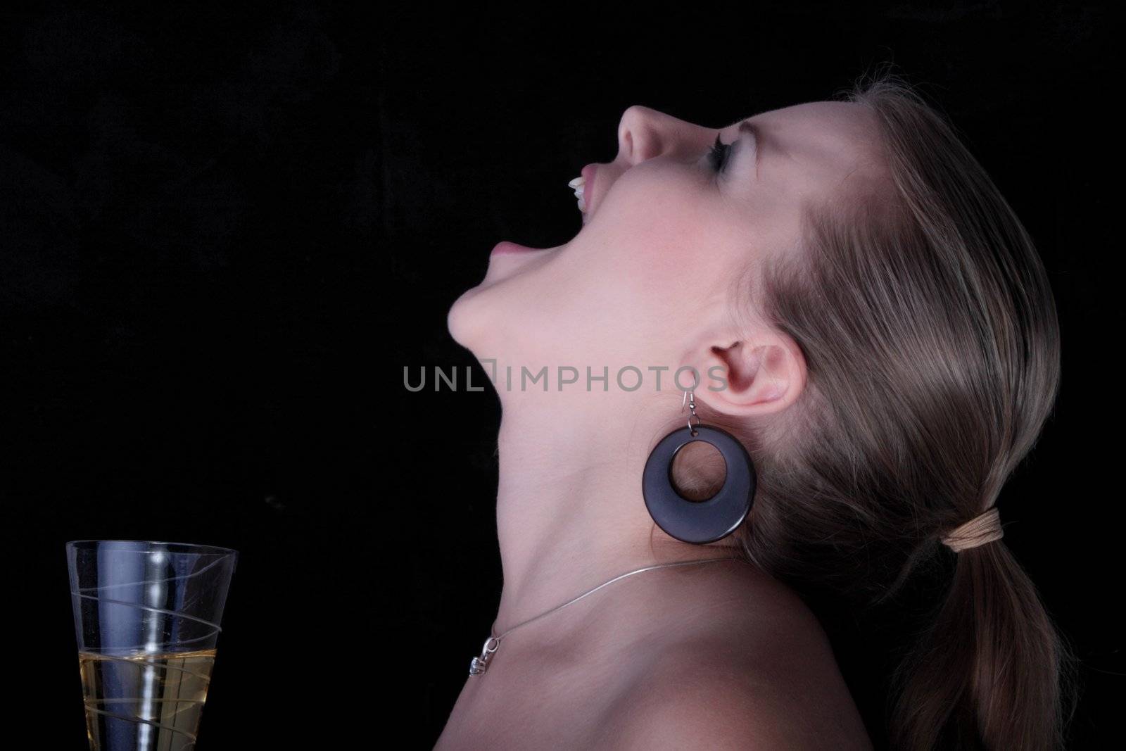 Beautiful blonde with a champagne glass screaming - on black background.