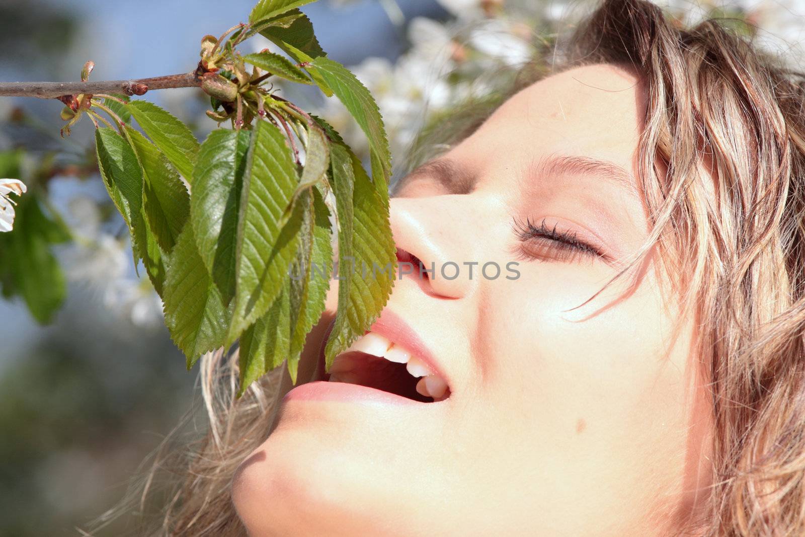 Beautiful blond woman between cherry tree with white flowers - portrait