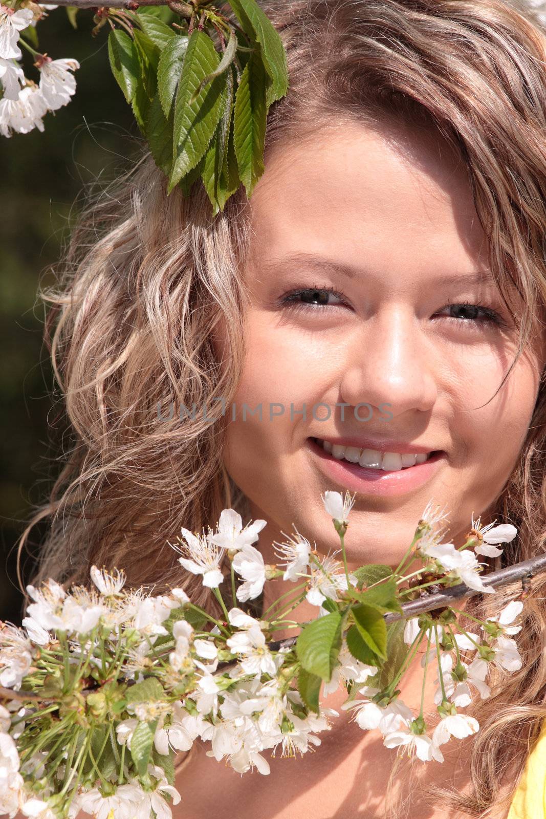 Beautiful blond woman between cherry tree with white flowers - portrait