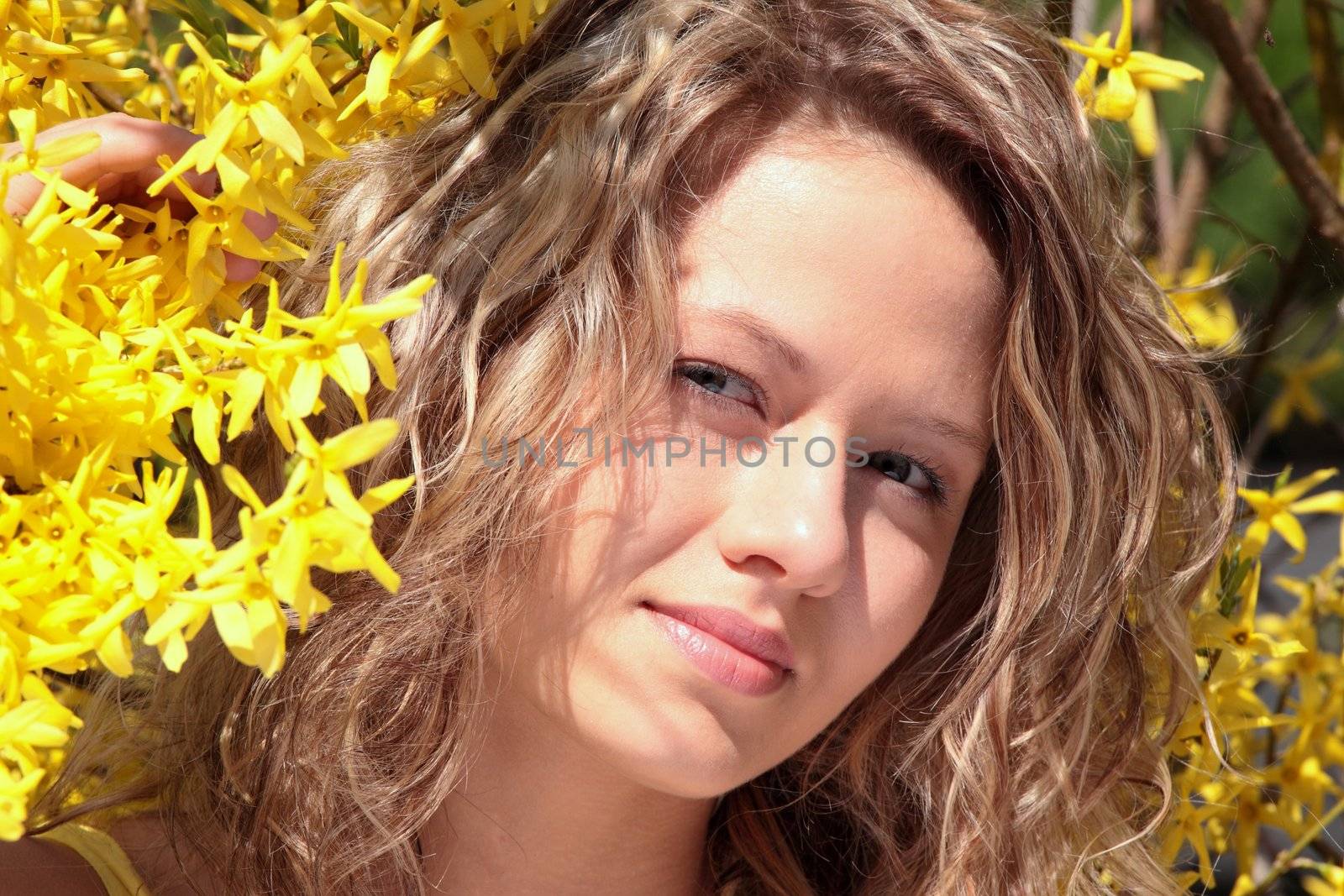 Blond young woman in yellow forsythia flowers by BDS