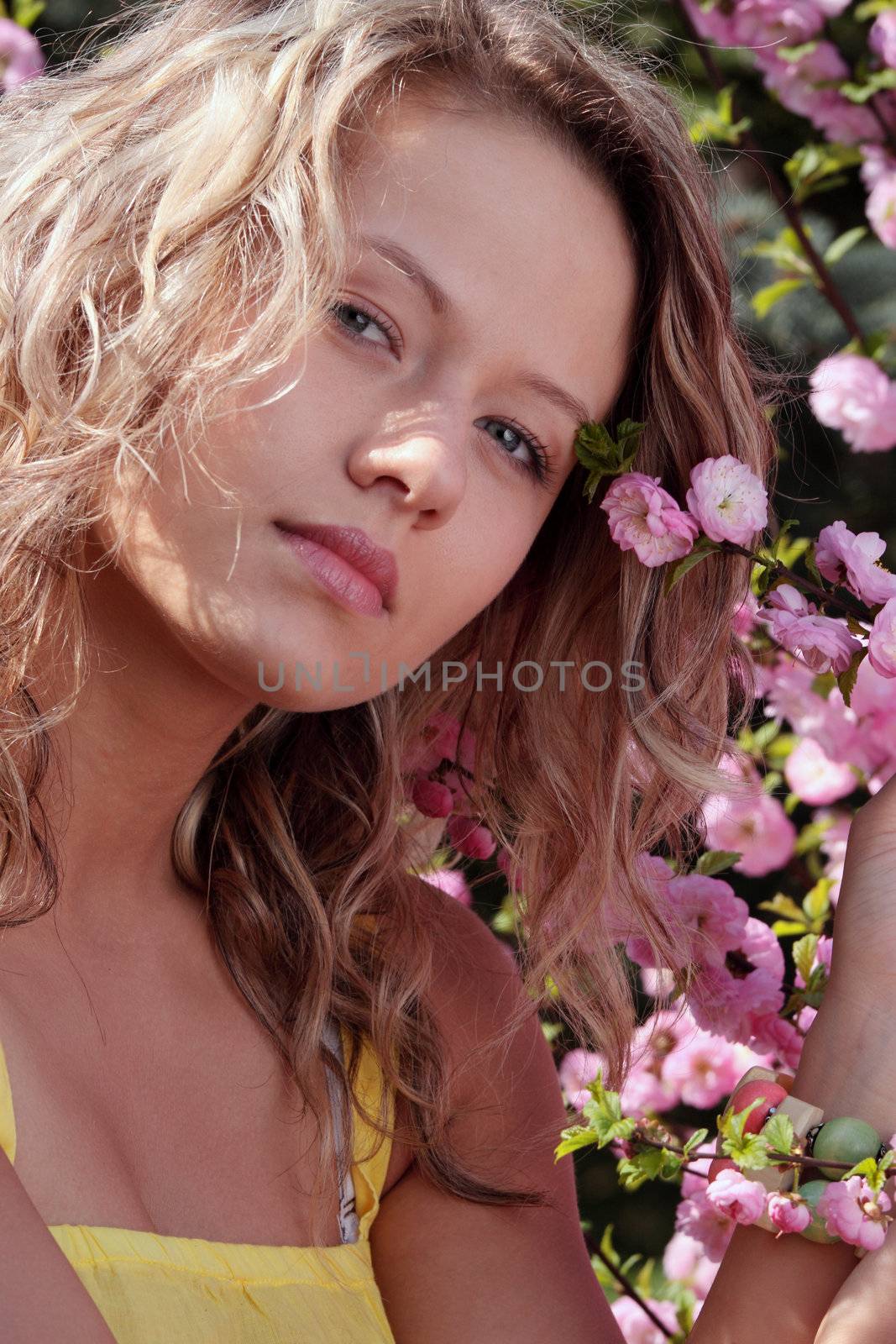 Beautiful blond woman between tree with pink flowers - portrait