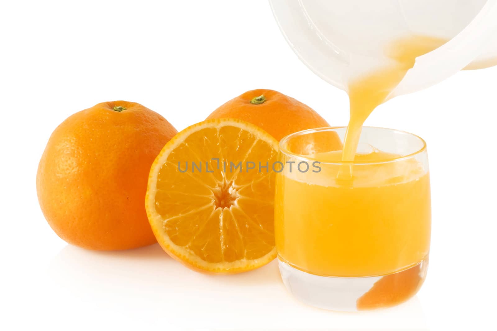 Pouring fresh pressed orange juice with oranges in the back; isolated on white.