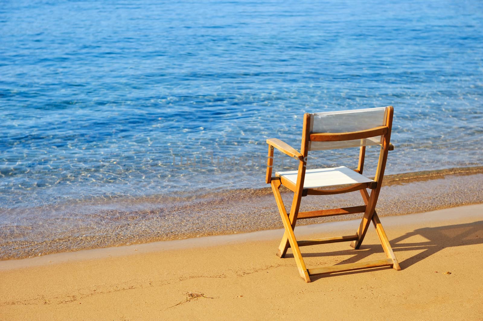 Chair on a golden sandy beach by akarelias