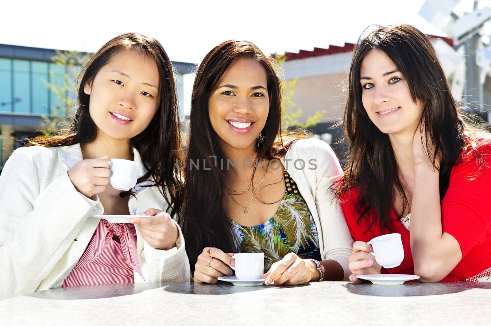 Group of girl friends sitting and having drinks at outdoor cafe