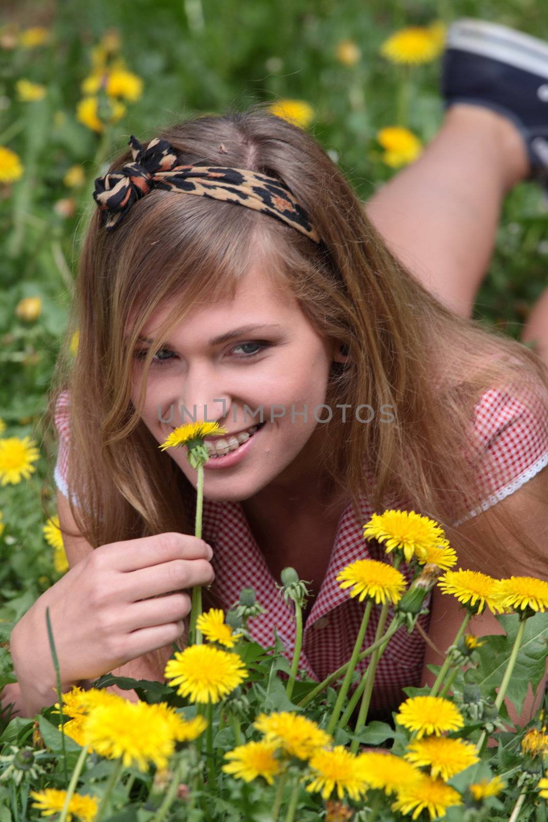 Beautiful young, blond woman relaxing in the grass and flowers