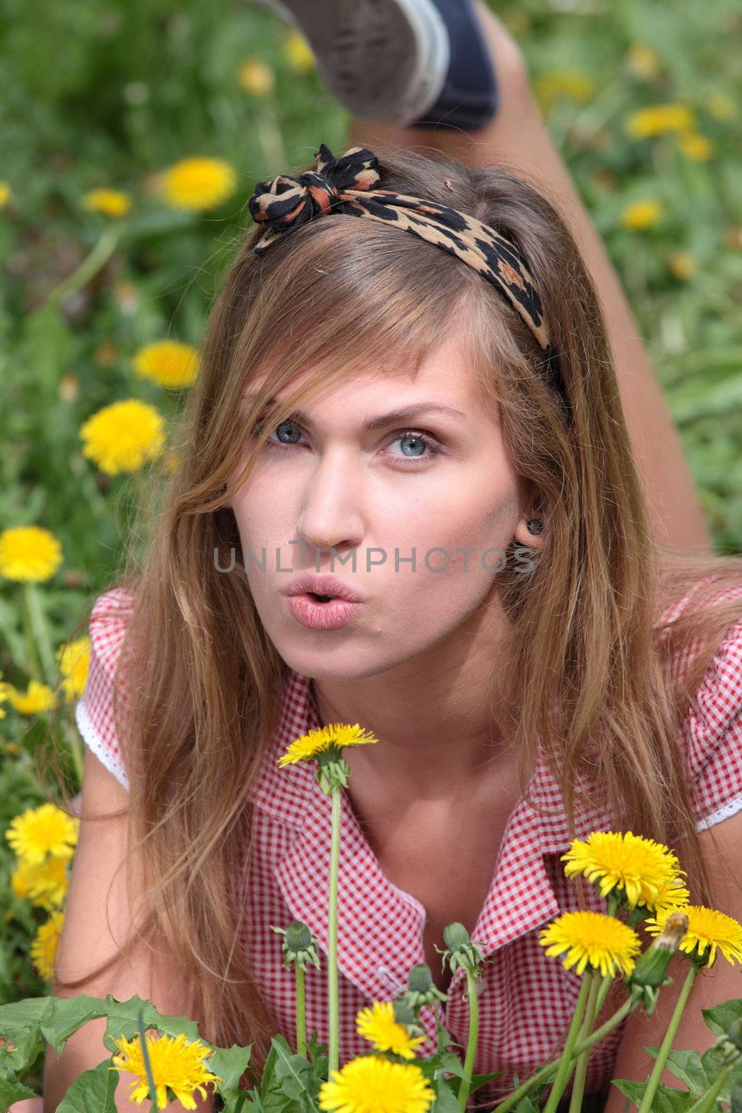 Beautiful young, blond woman relaxing in the grass and flowers