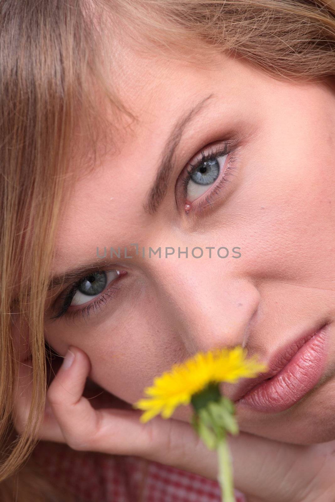 Beautiful young, blond woman relaxing in the grass and flowers