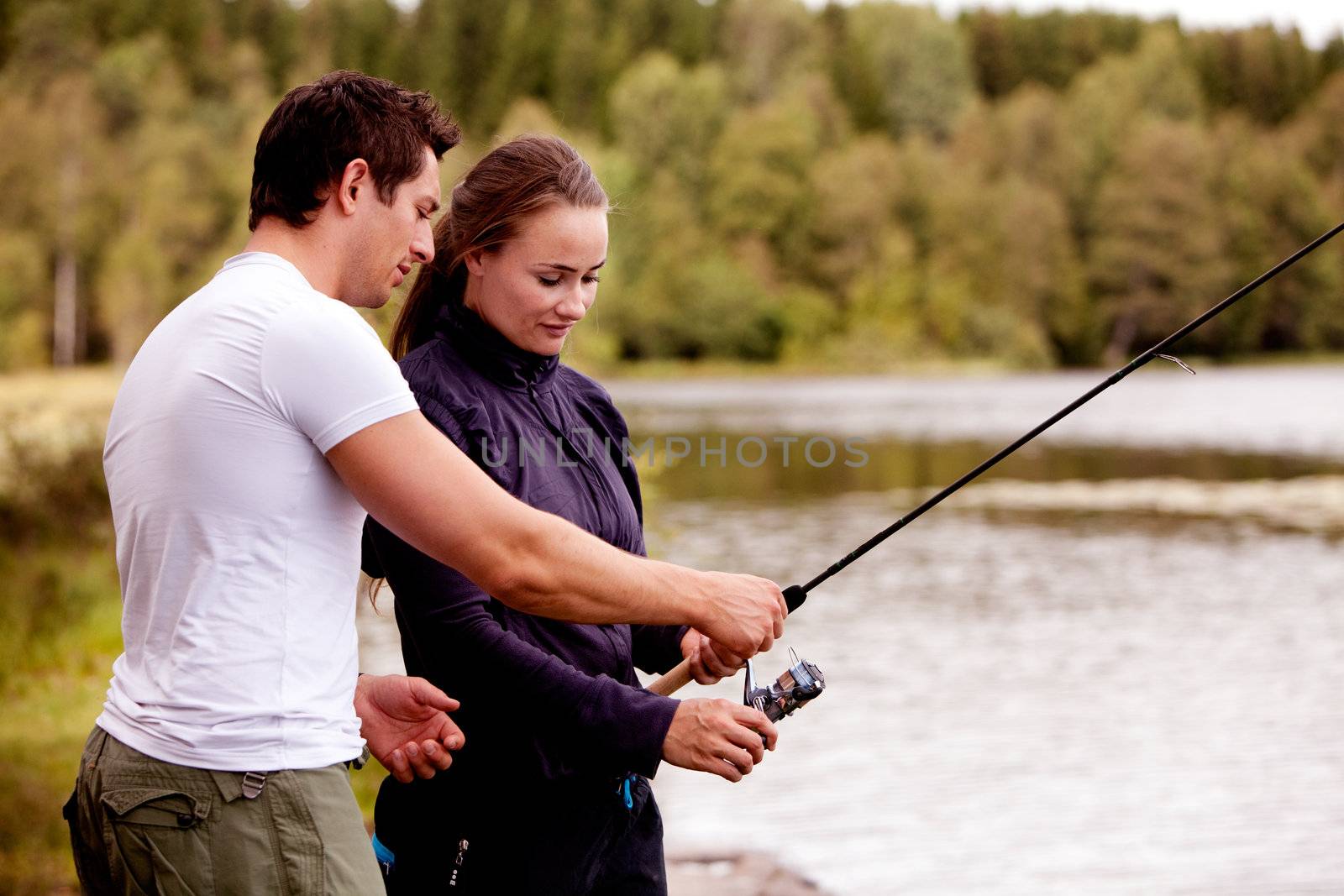 A man showing a woman how to fish
