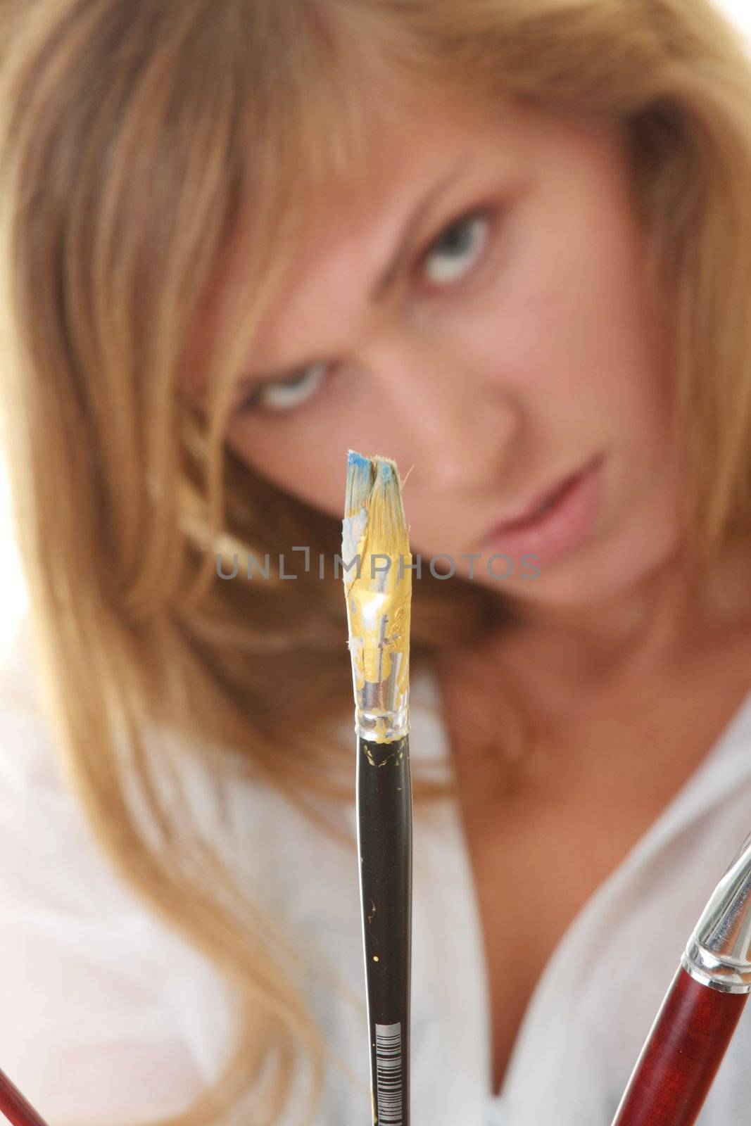 A female blond artist in white uniform with brushes - painting