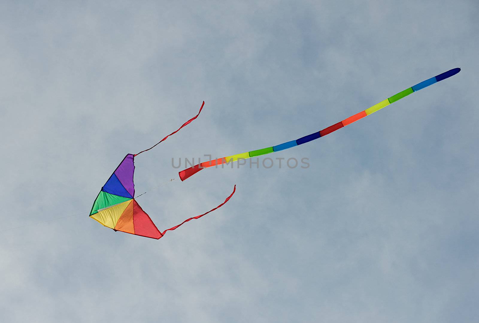 Colorful rainbow kite flying in the air with a gorgeous blue summer sky in the background.  Room for text.