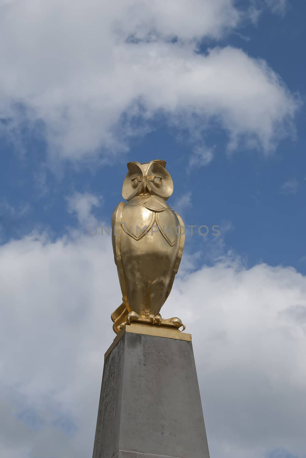 A Gold Coloured Statue of an Owl against a summer sky