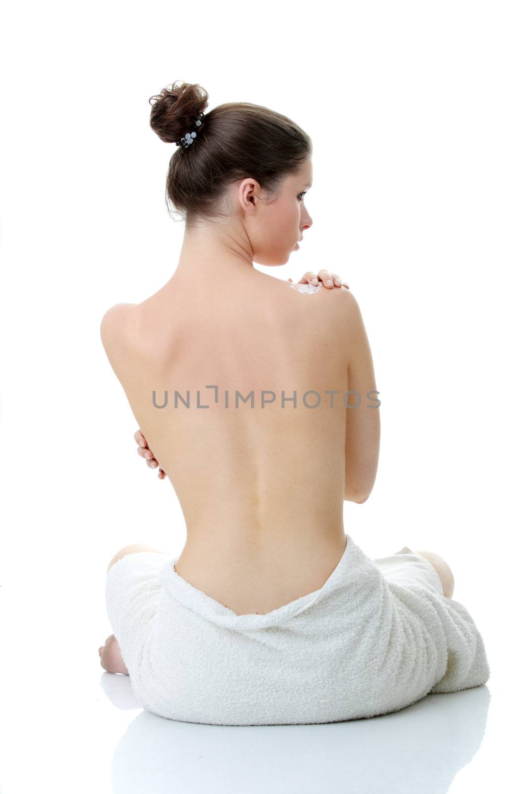 Skincare concept: back of beautiful nude woman with soft skin putting skincare product (cream) on her back