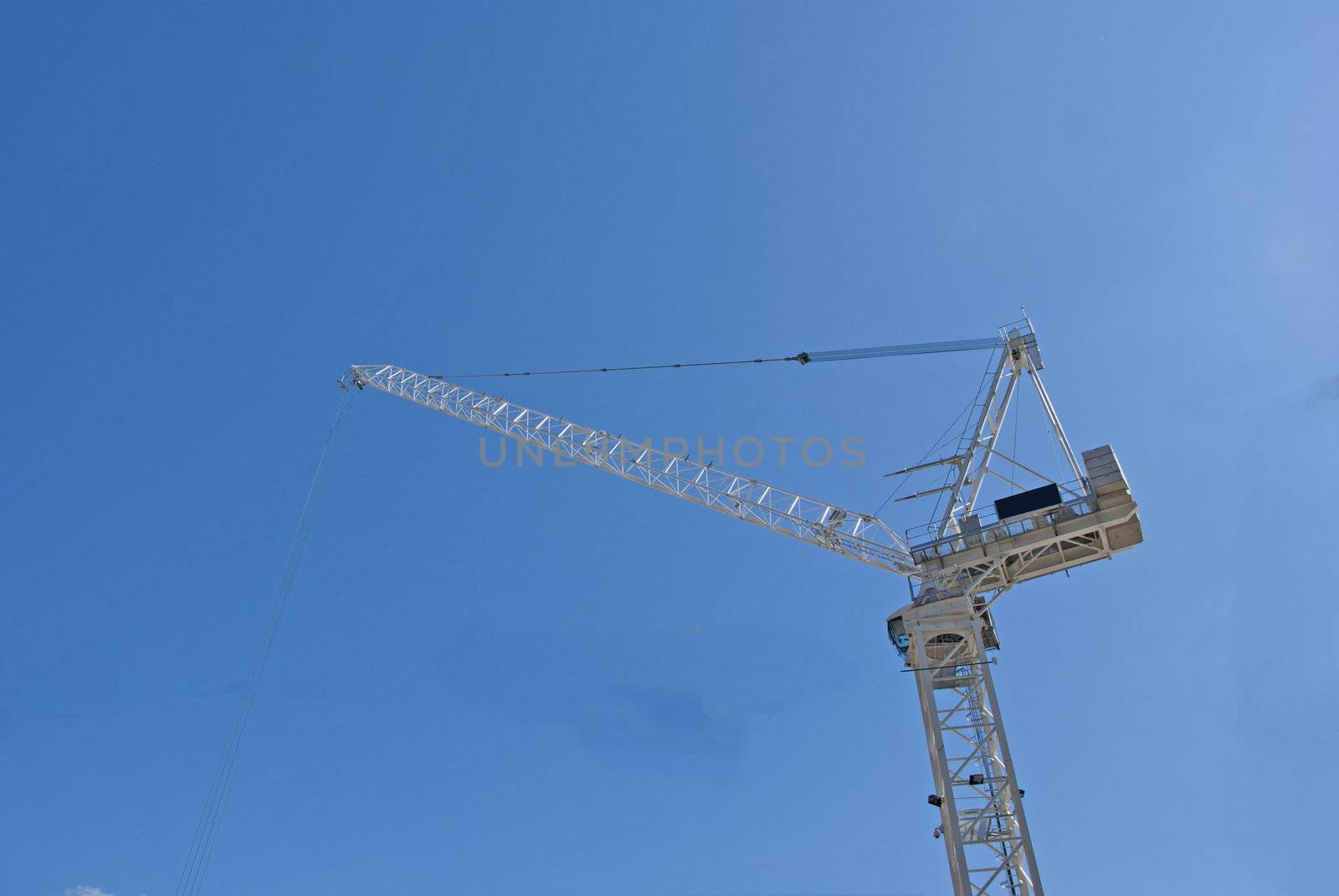 A White Tower Crane of a city construction site against a blue sky