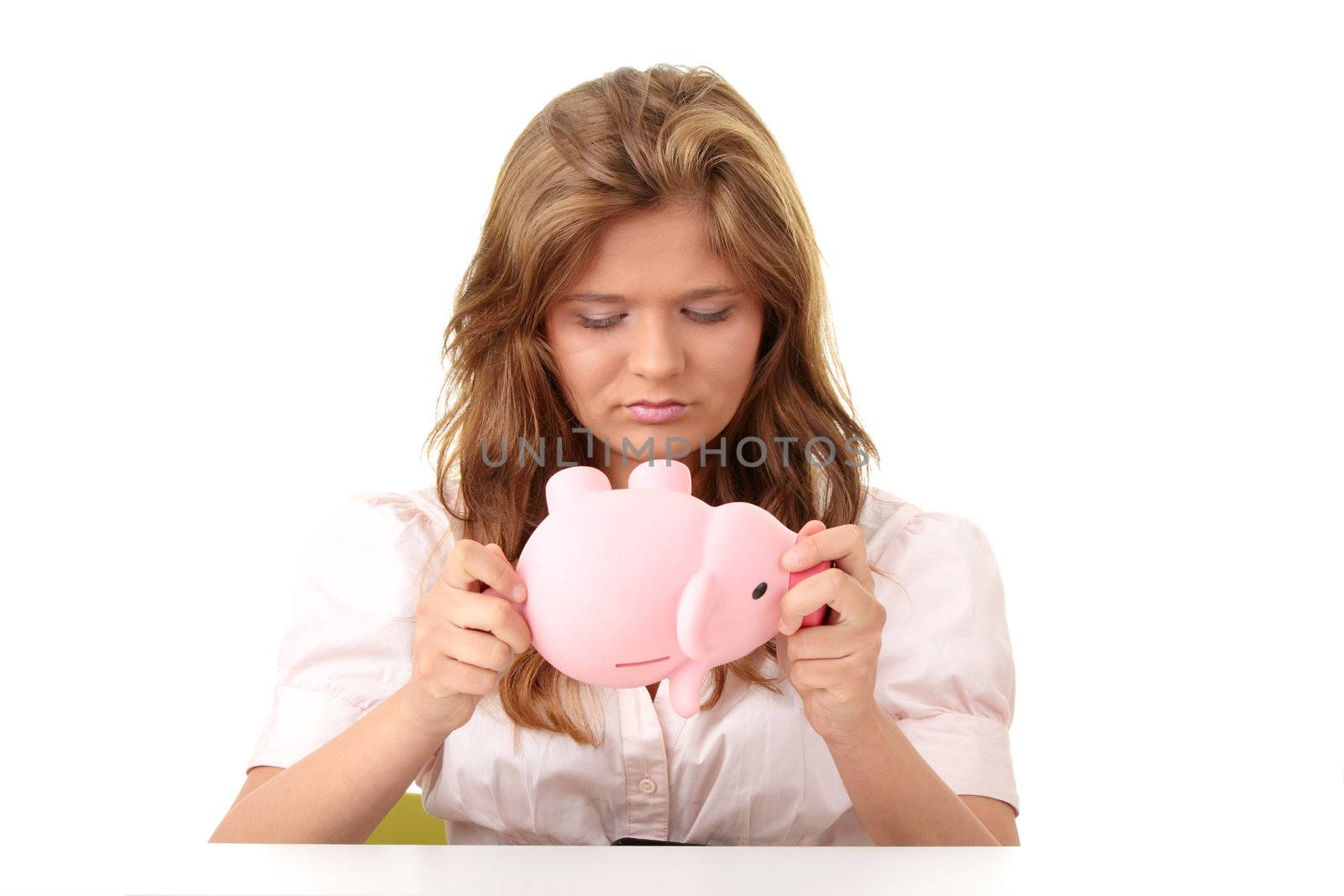 Young beautiful woman siting at the desk with piggy bank (money box), isolated on white background