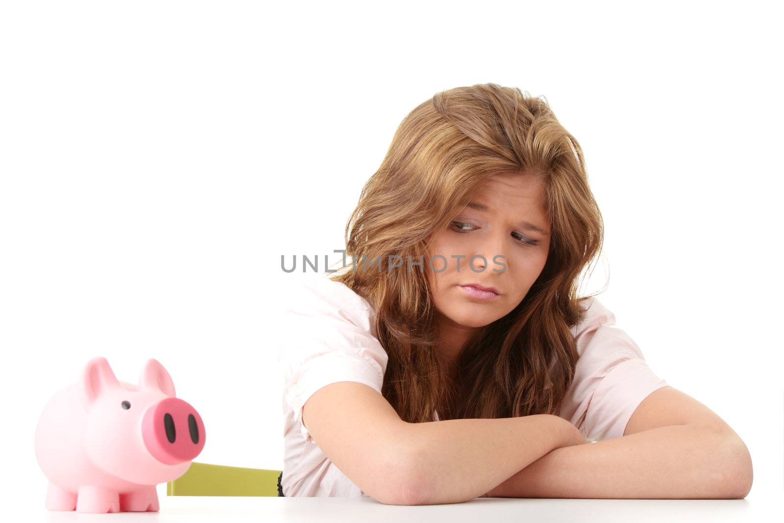 Young beautiful woman siting at the desk with piggy bank (money box), isolated on white background