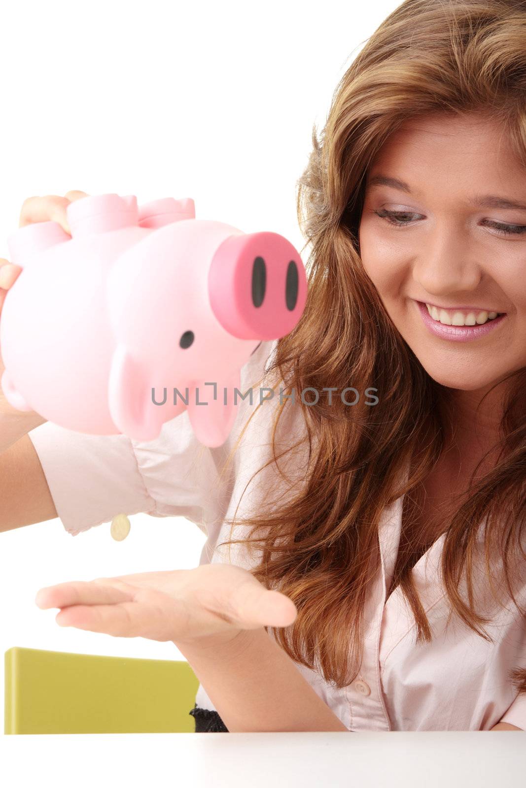 Young beautiful woman siting at the desk with piggy bank (money box), isolated on white background