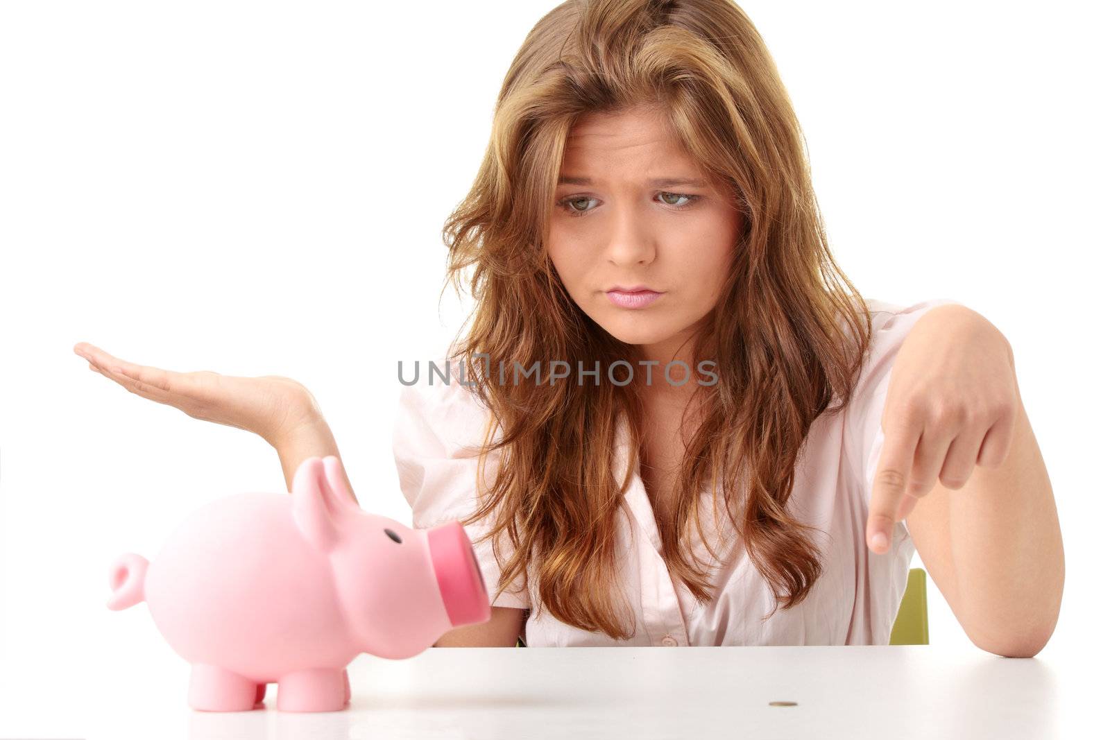 Young beautiful woman siting at the desk with piggy bank (money box), isolated on white background