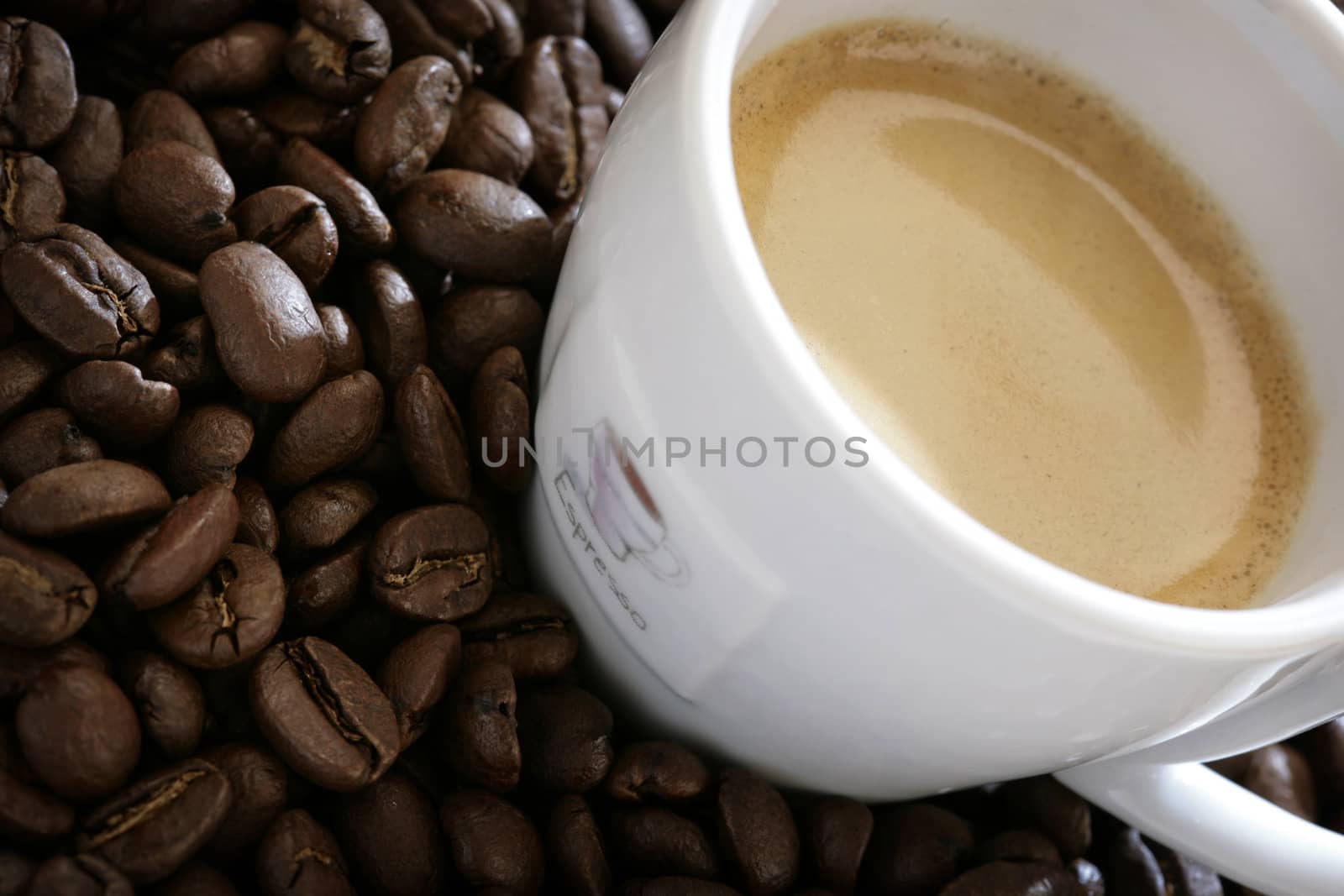 close-up of espresso cup with coffee beans around it