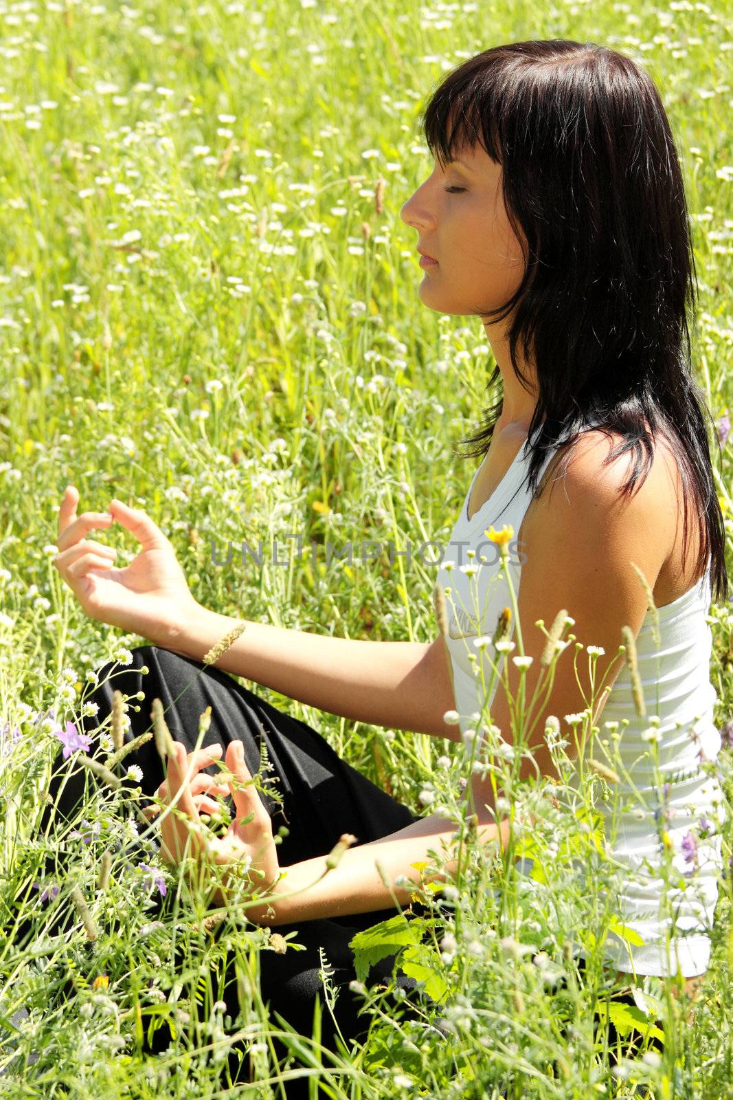 Young woman in pose lotus meditating outdoor.