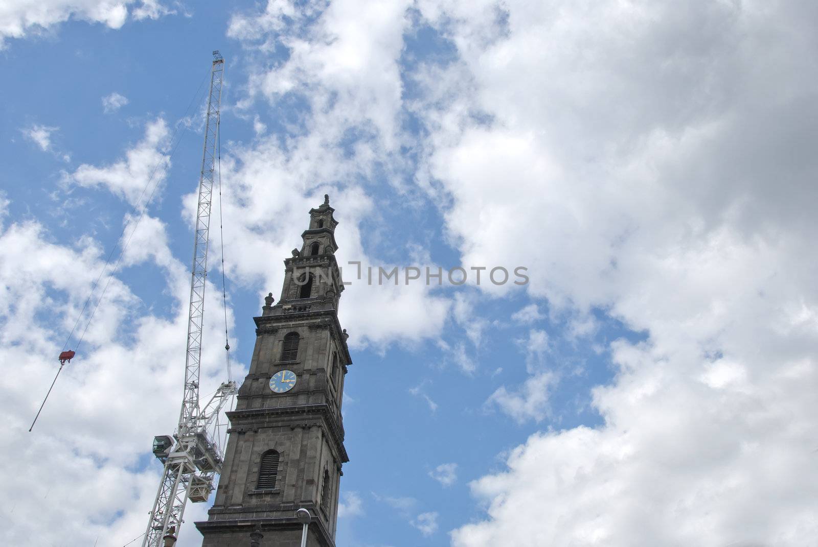 A White Heavy Lift Crane alongside a Victorian Clocktowerwith a blue and gold clock