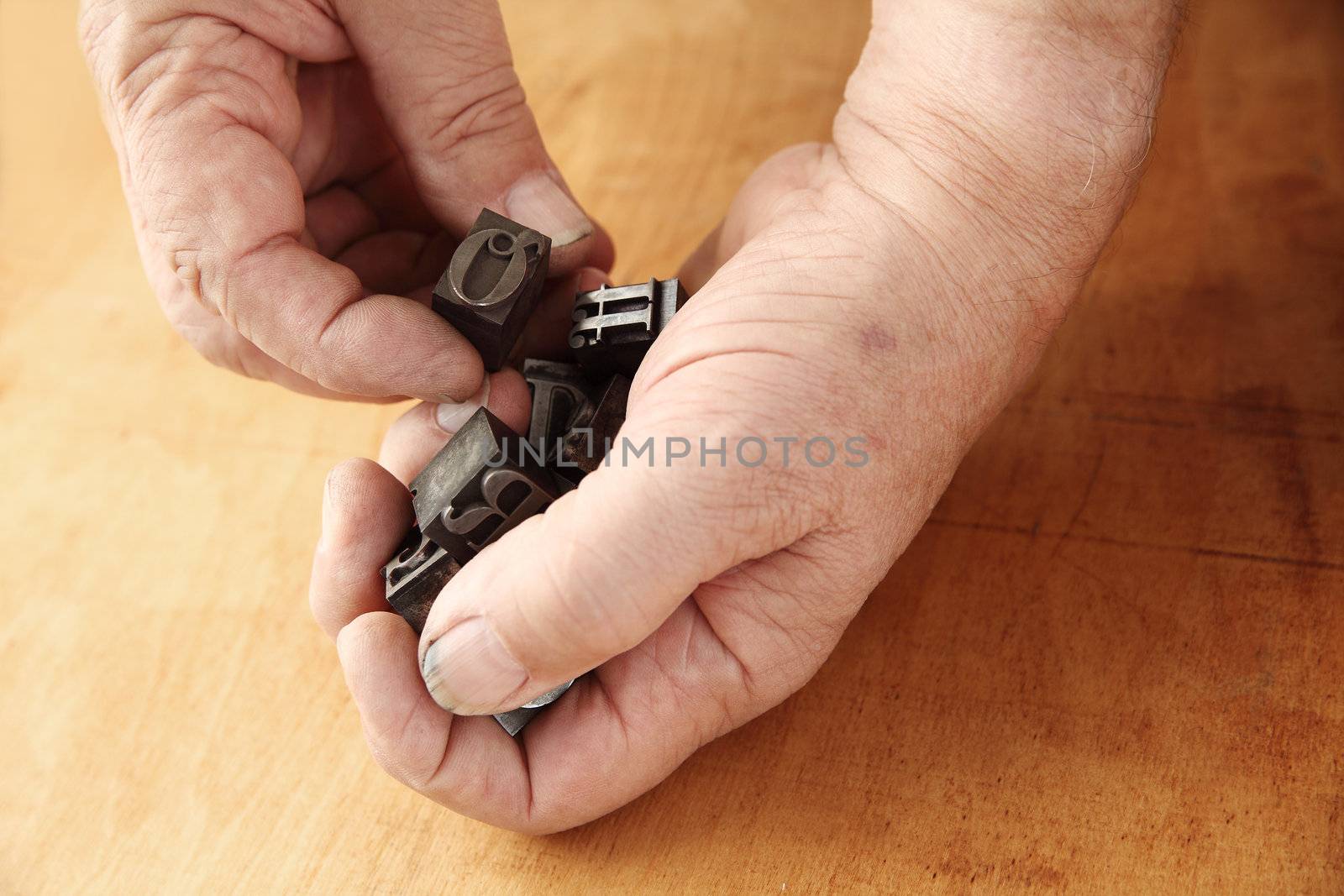 printer's ink-stained hands holding metal type pieces