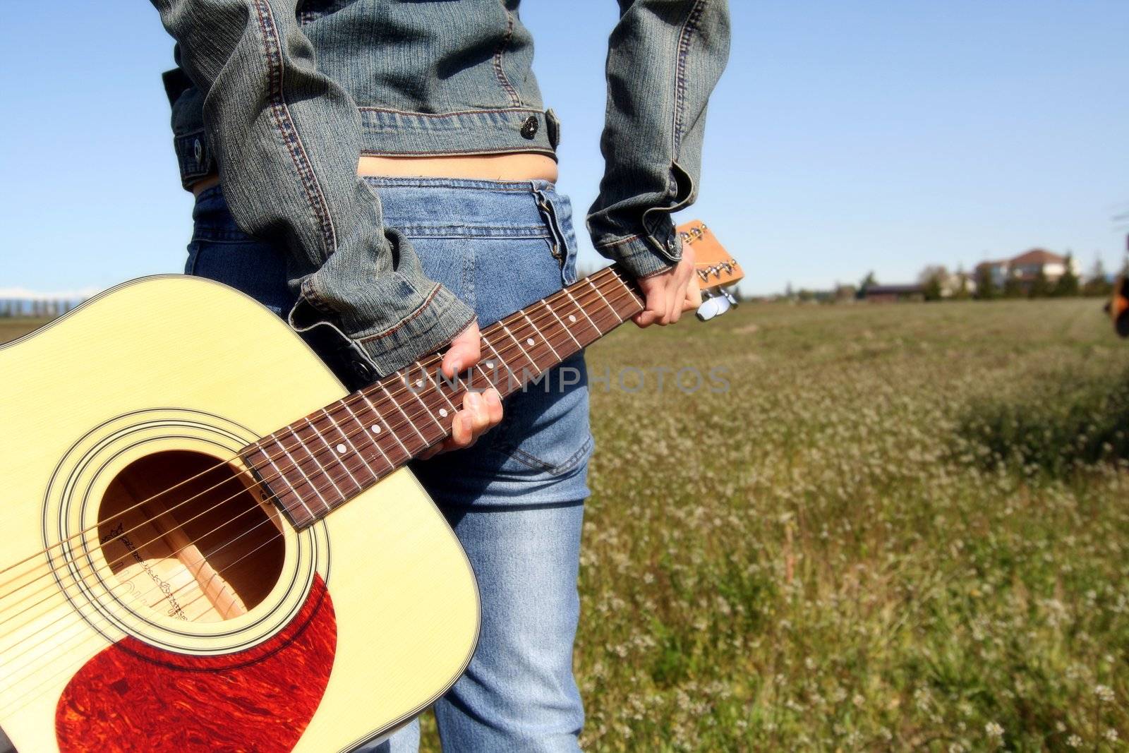 A woman holding a guitar looking at an empty field