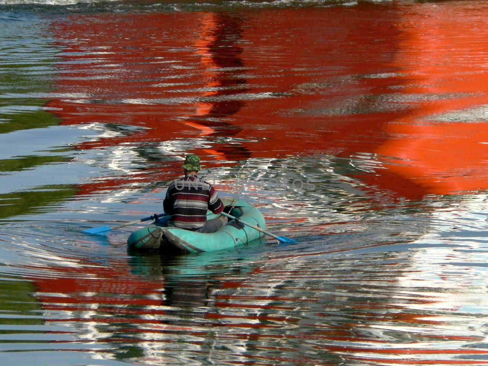 The Colorful reflection on water and fisherman in boat.