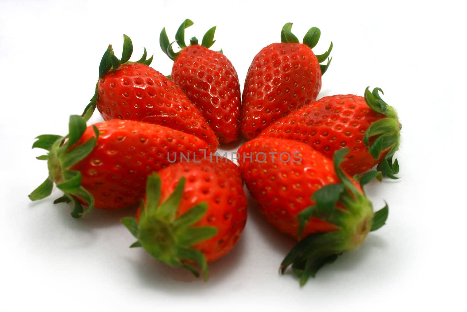 Steven brightly red strawberries on a white background form up a pattern.