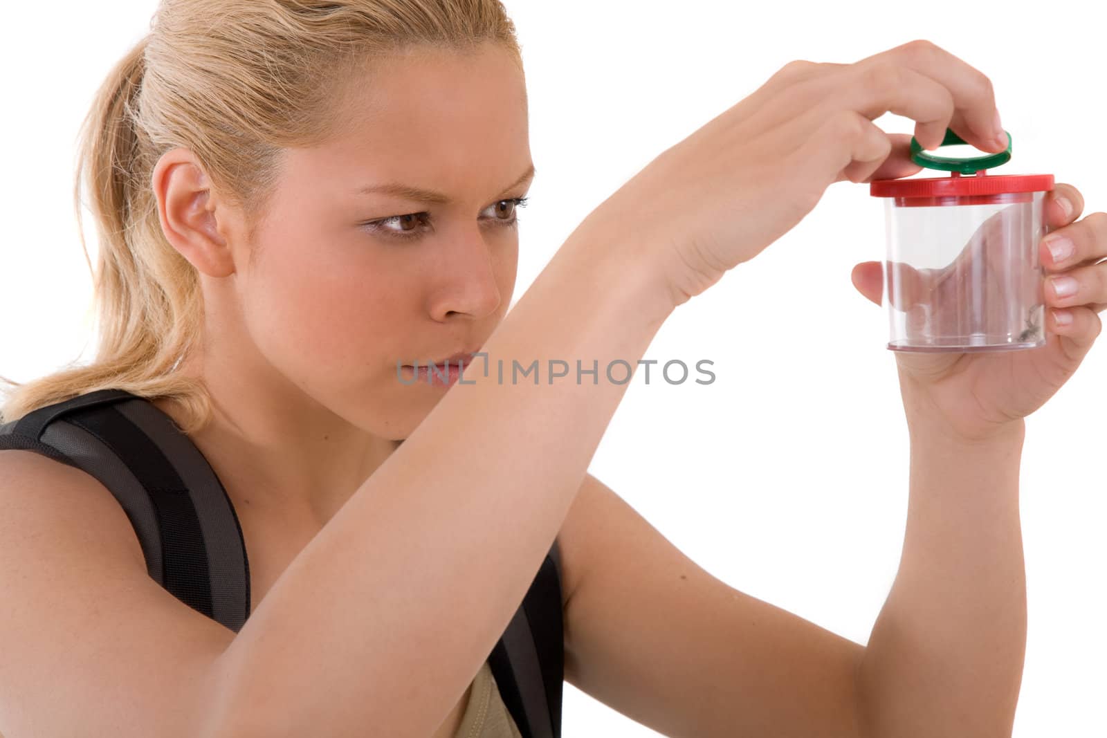 Beautiful blond woman dressed in jungle outfit examining a small spider in a loupe can