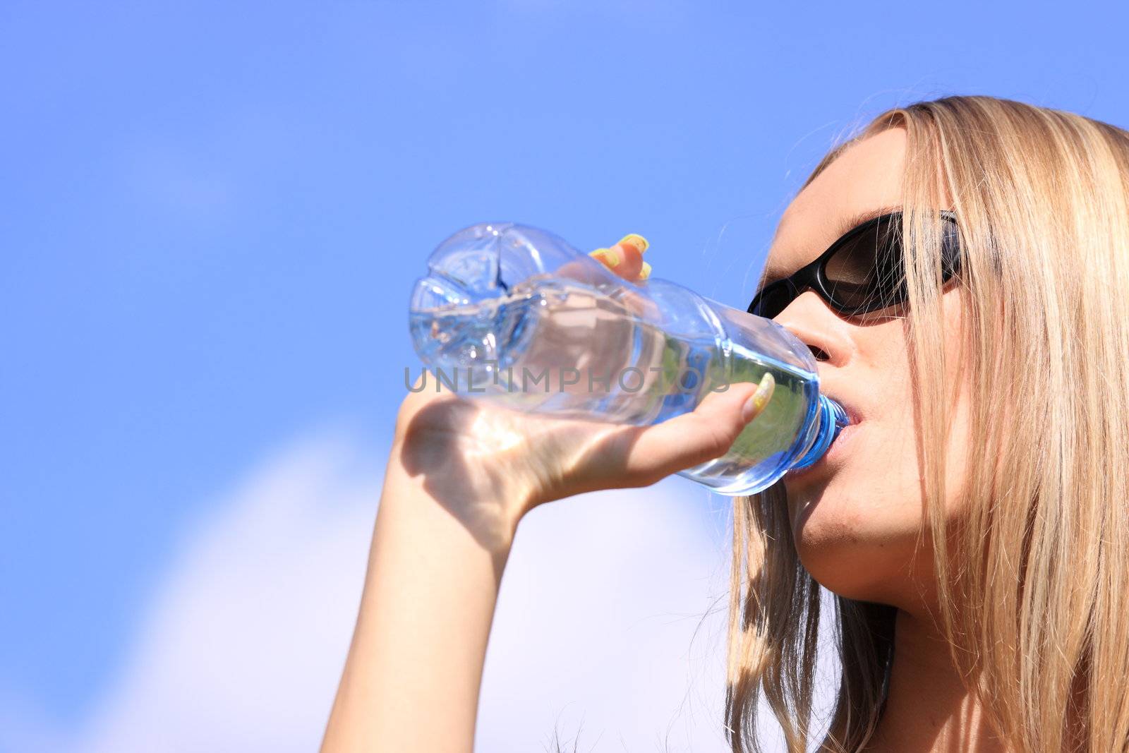 Girl drinking water against blue sky in sunny day