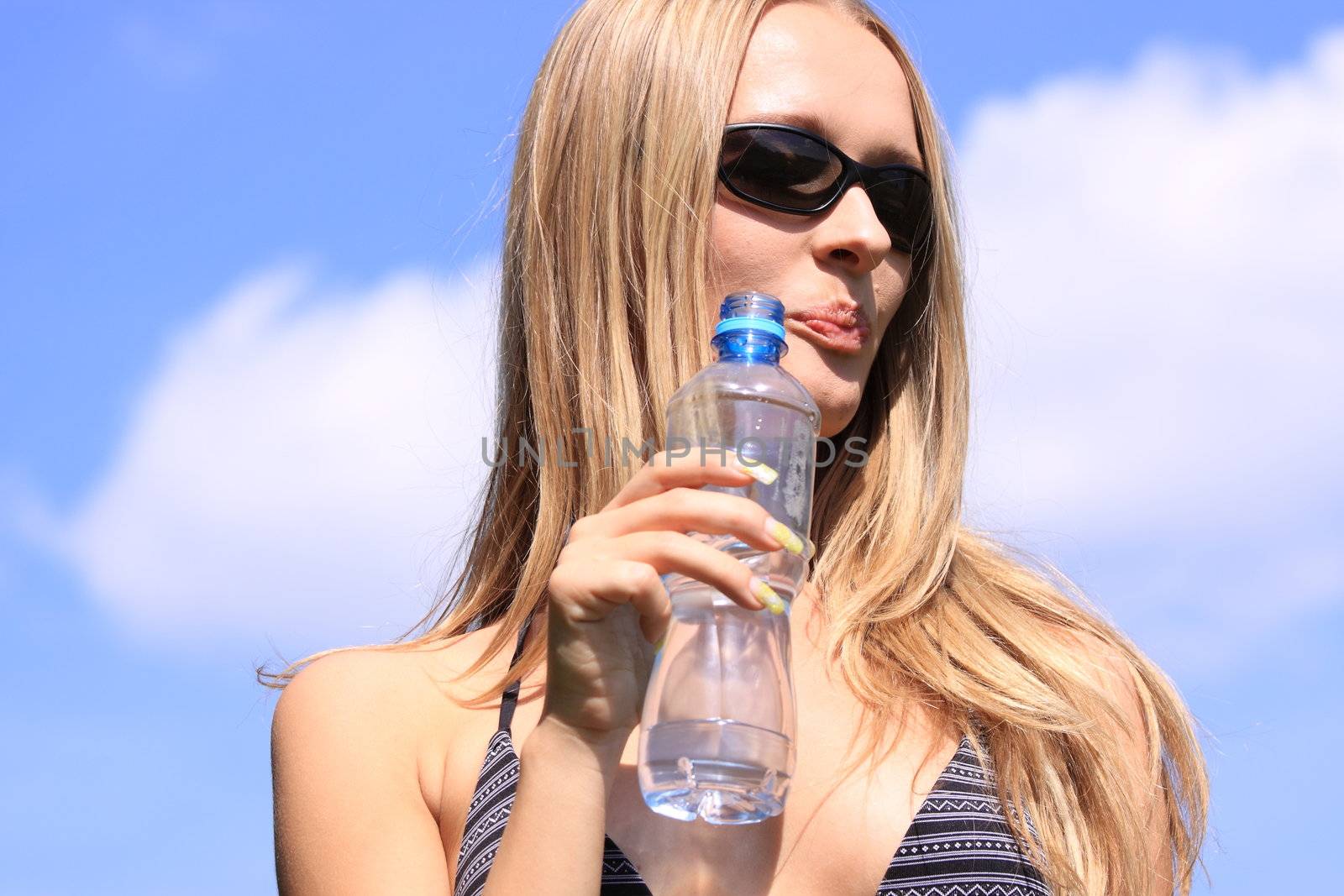 Girl drinking water against blue sky in sunny day
