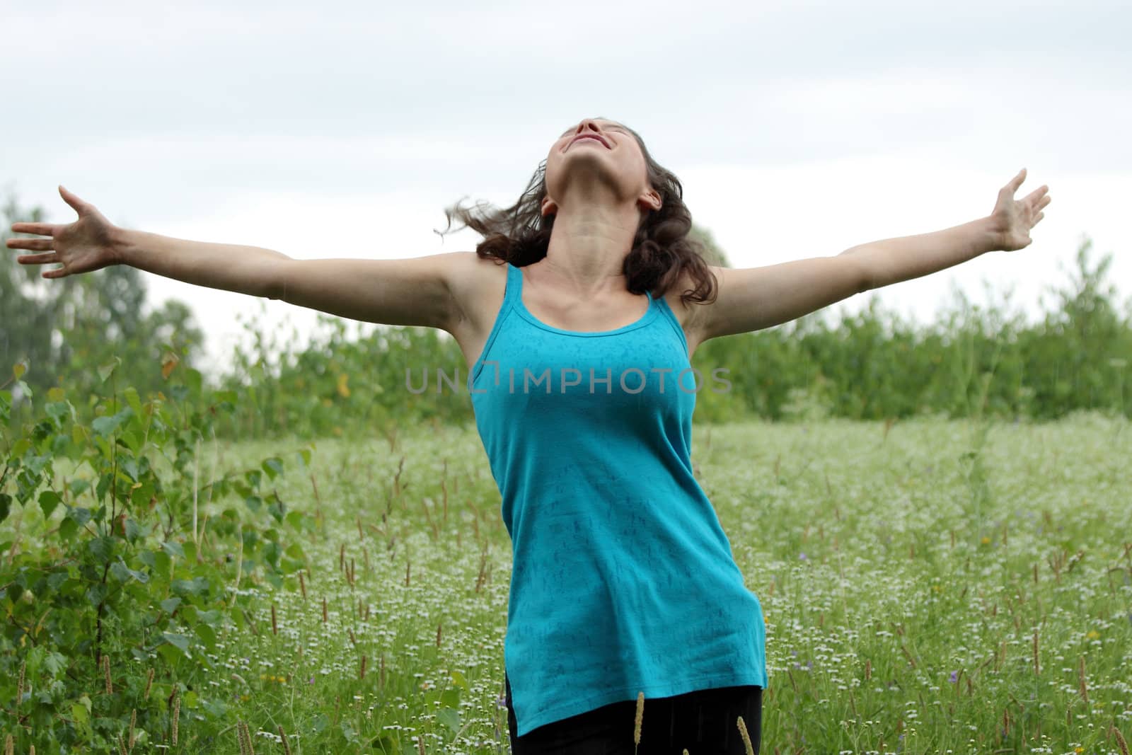 Beautiful young woman relaxing in the grass (rain in summer)