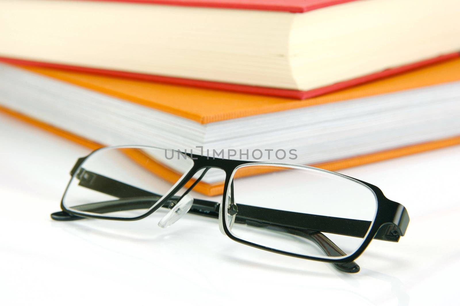 Reading glasses and books isolated against a white background