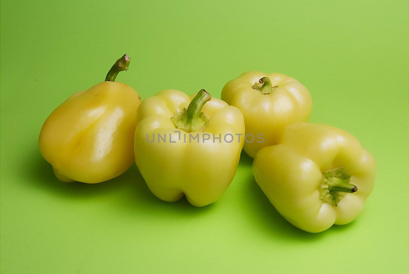 Group of yellow peppers on green background