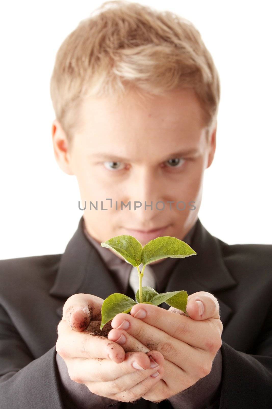 Businessman in dark suit holding smal plant in his hands - growth concept