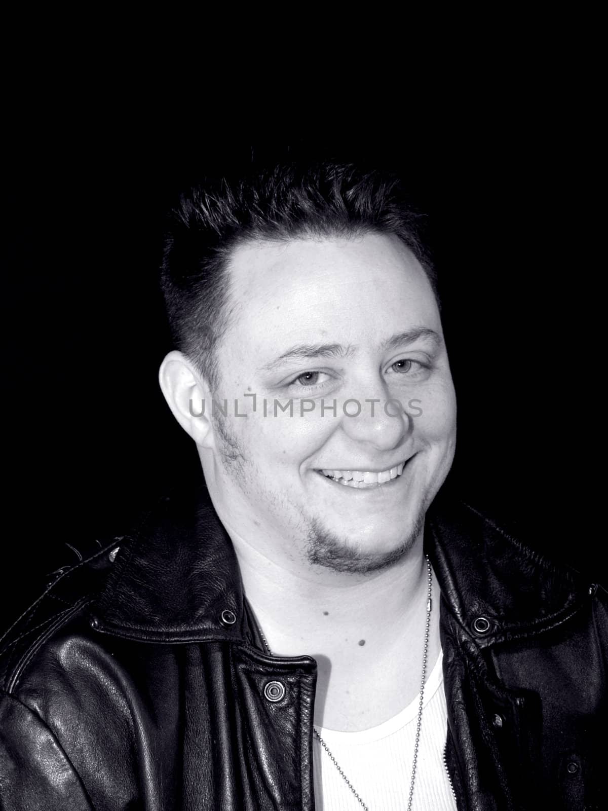a man in a leather jacket smiling in black and white.