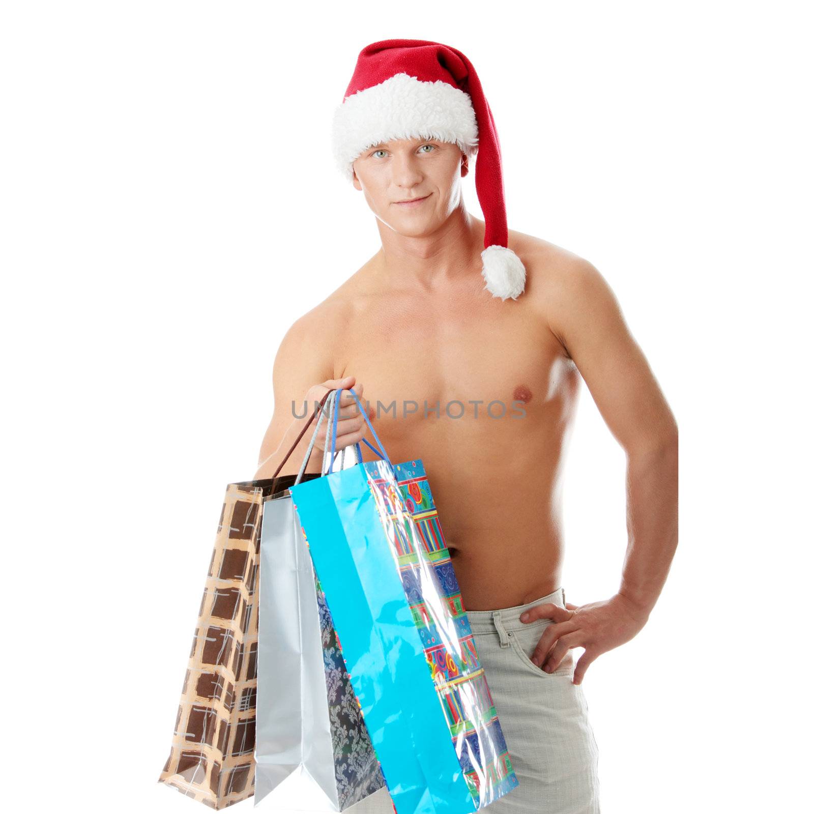 Sexy muscular shirtless man in Santa Claus hat with shopping bags isolated on white