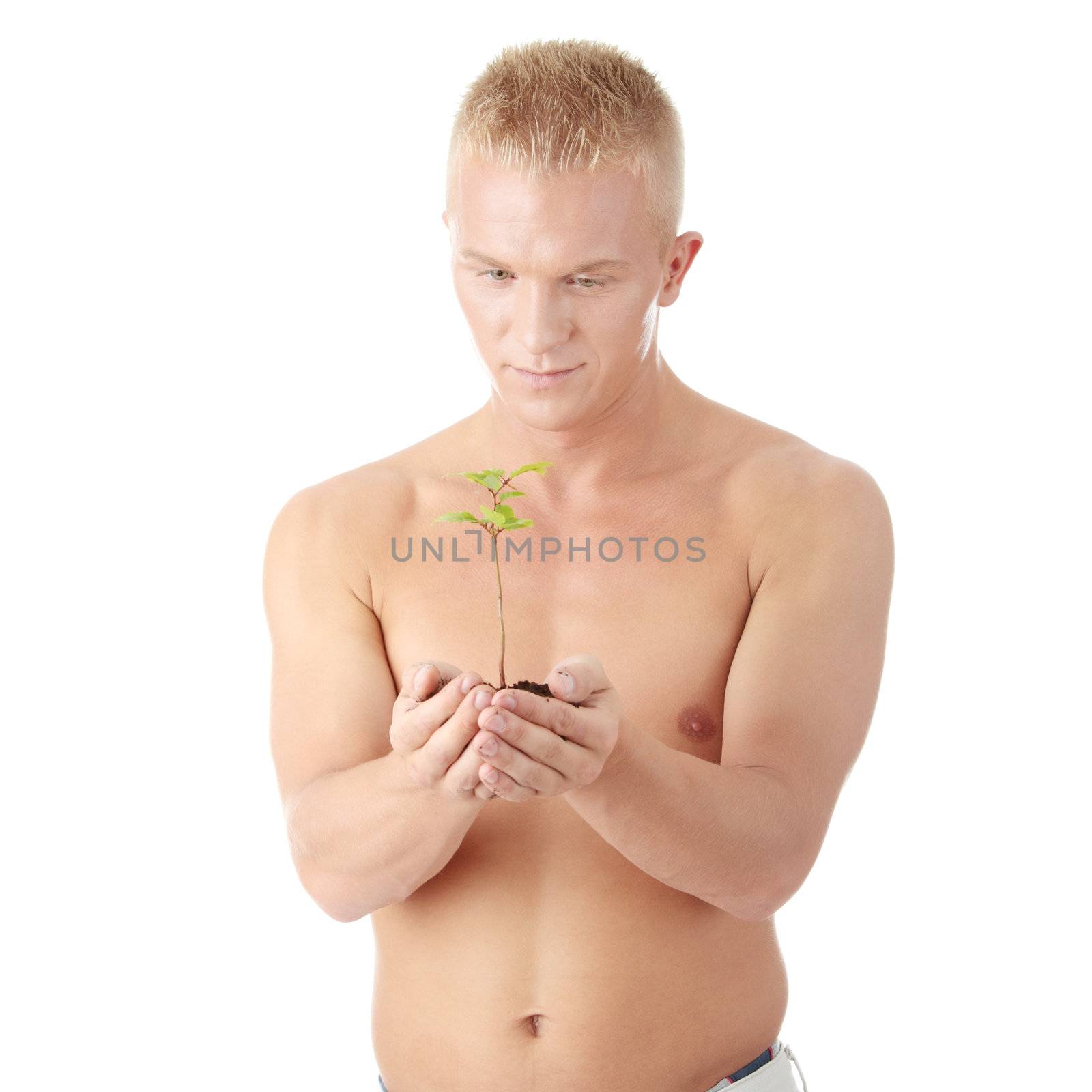 Muscular man holding small plant and soil in his hands. Isolated on white in studio.