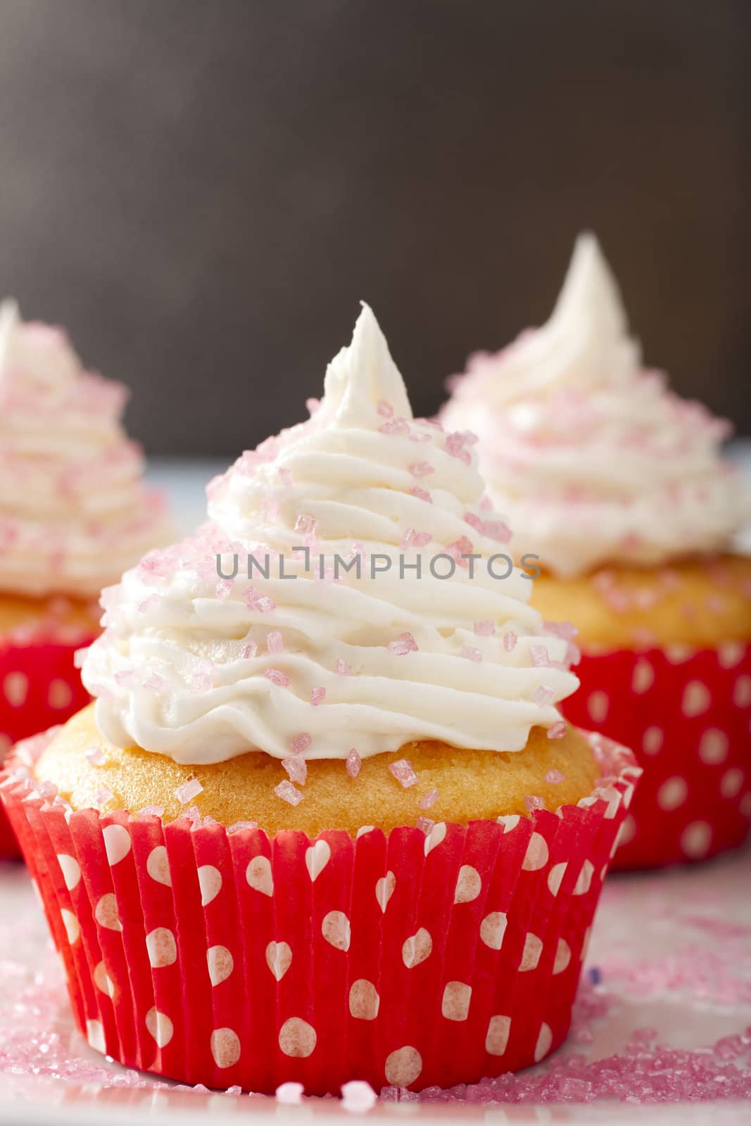Yellow cupcake in red and white polka dot cupcake paper topped with white frosting