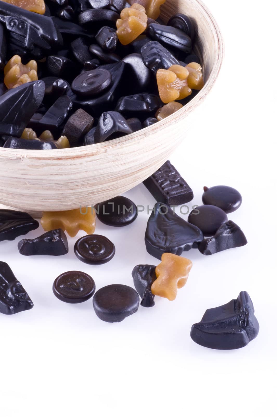 Close up of a part of a bowl filled with liquorice, isolated on white.