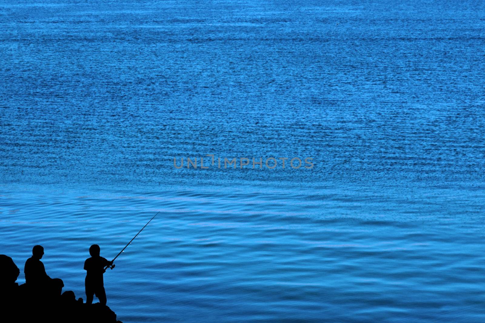 a silhouette of a father and son fishing of the rocks in ireland