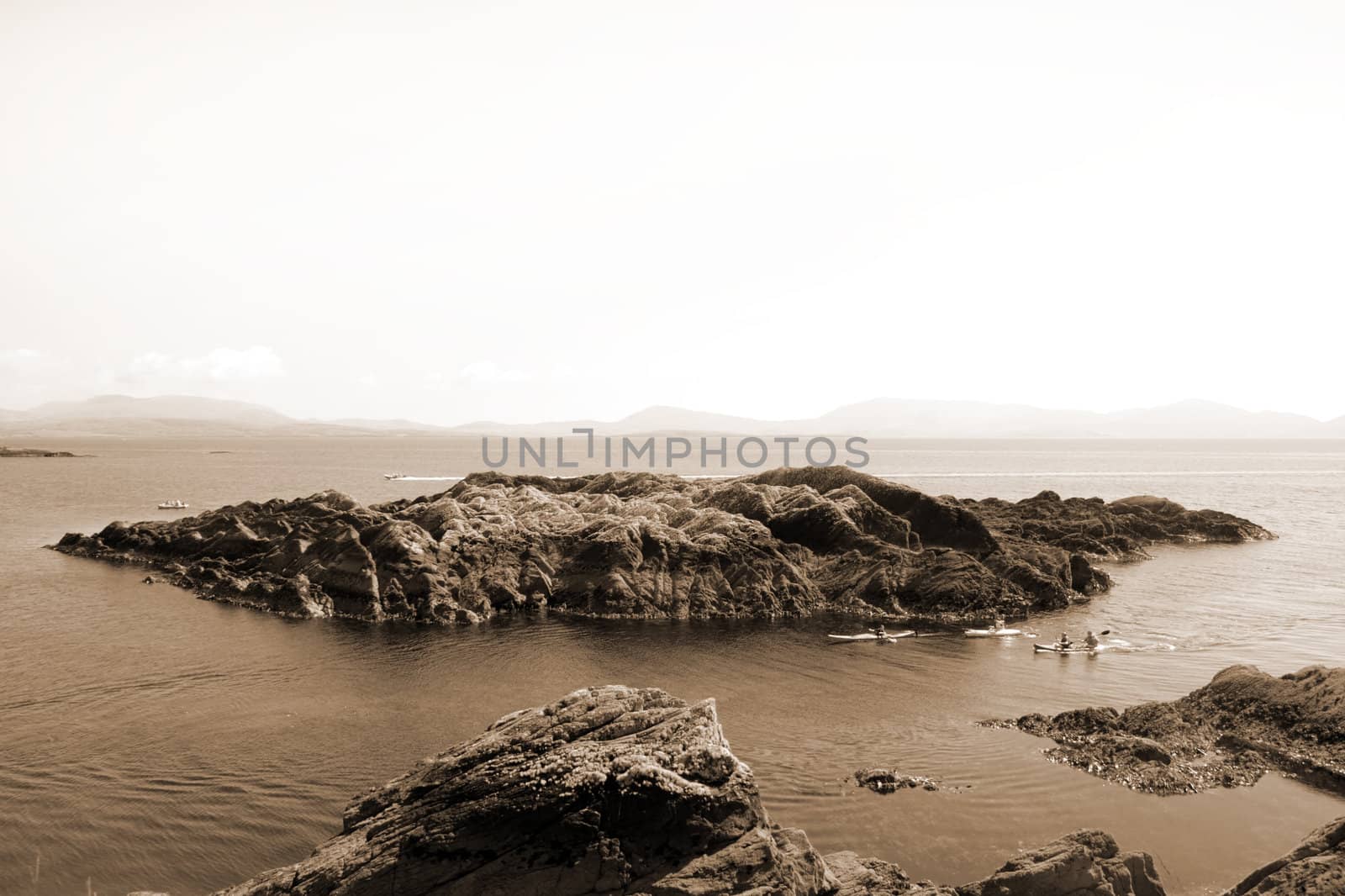 kayaks in a scenic view in kerry ireland of rocks islands and sea with mountains against a beautiful blue cloudy sky