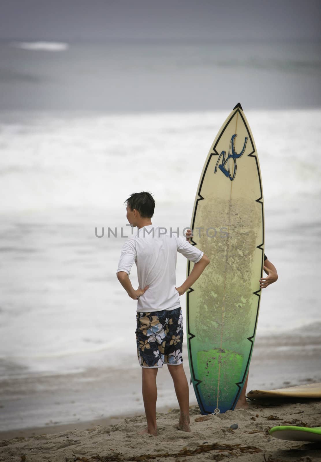young surfer standing on the beach with surfboard