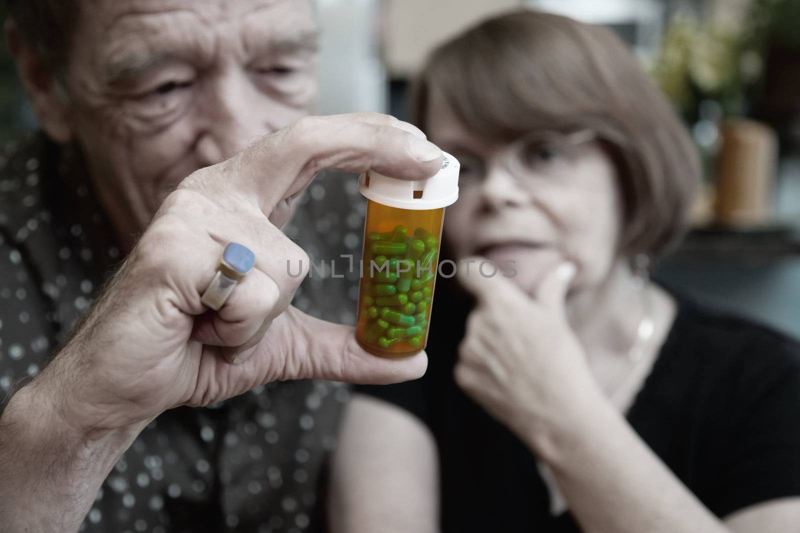 Senior couple at home with prescription bottle, focus