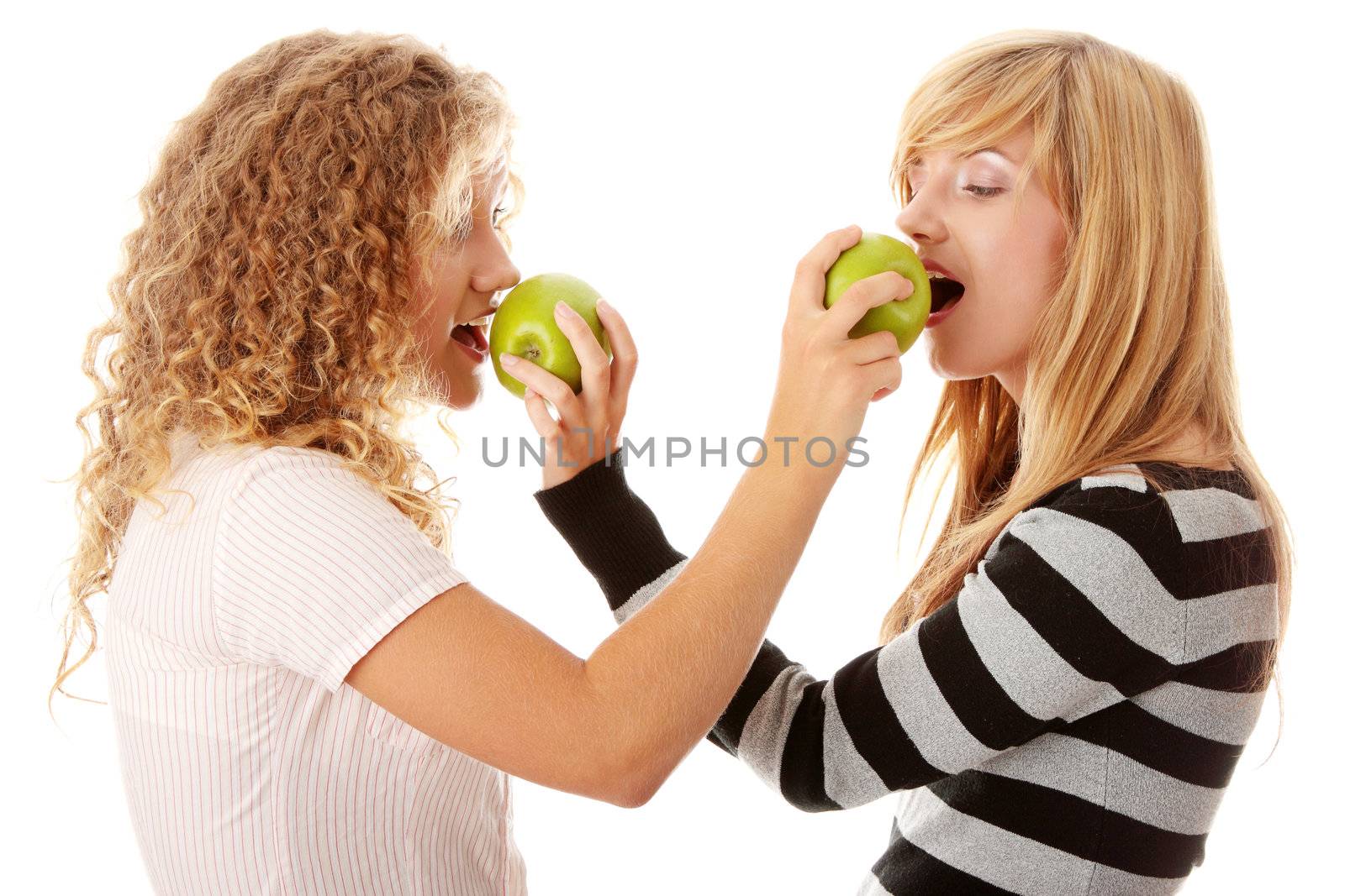 Two teen girlfriends eating green apples by BDS