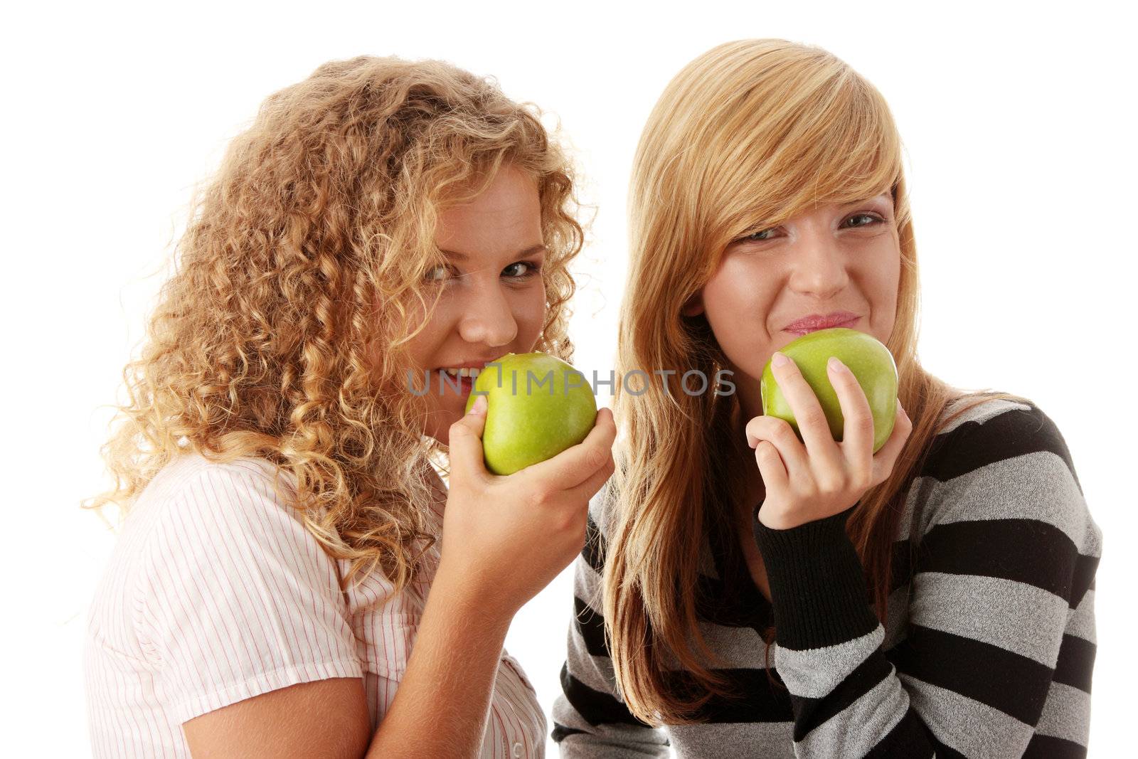 Two teen girlfriends eating green apples by BDS