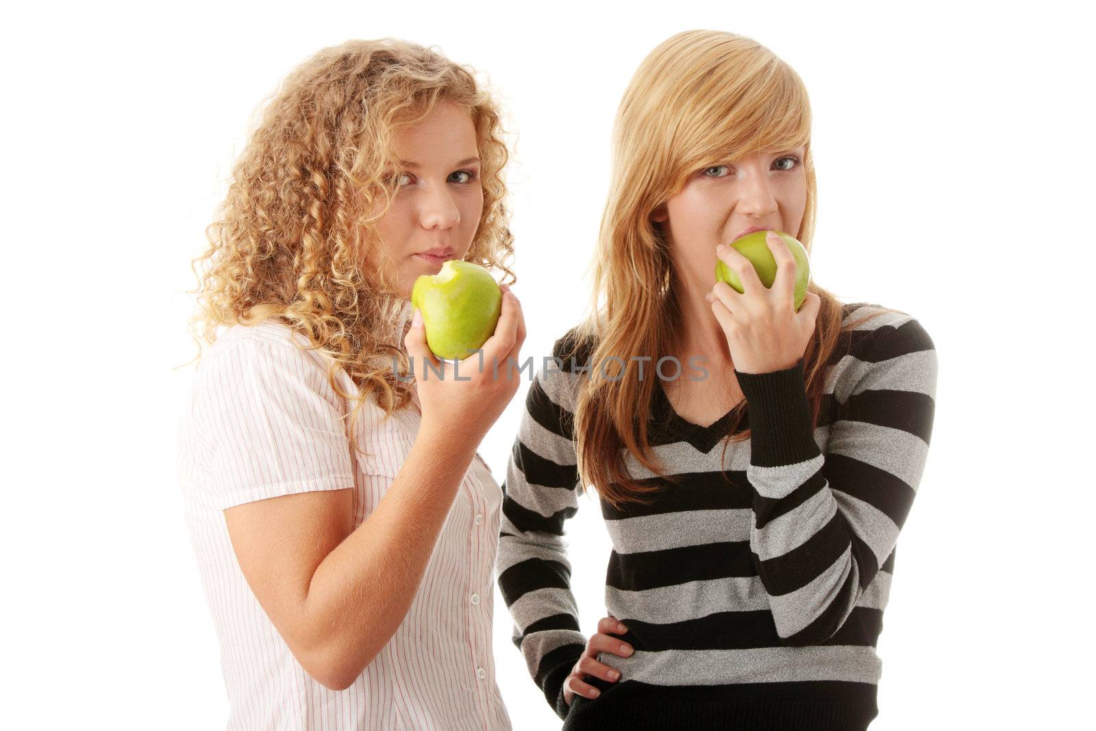 Two teen girlfriends eating green apples isolated